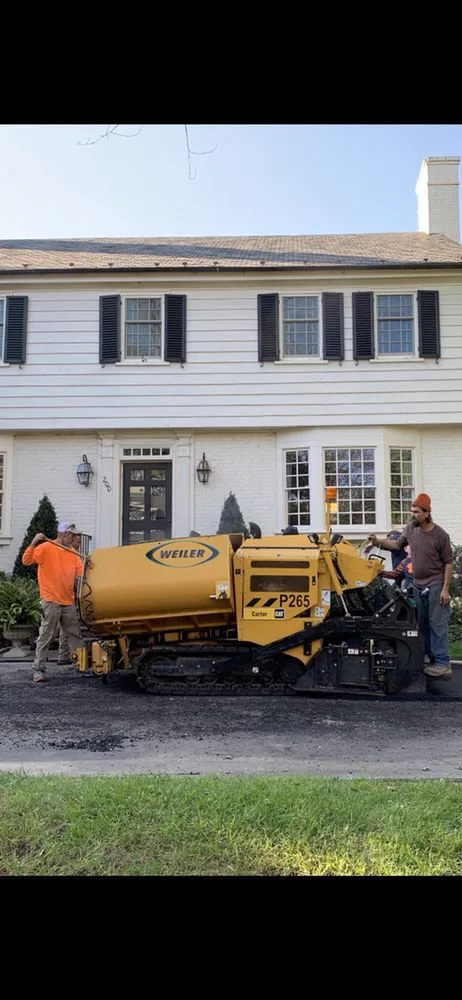 Crew and paver working a driveway at a white colonial home